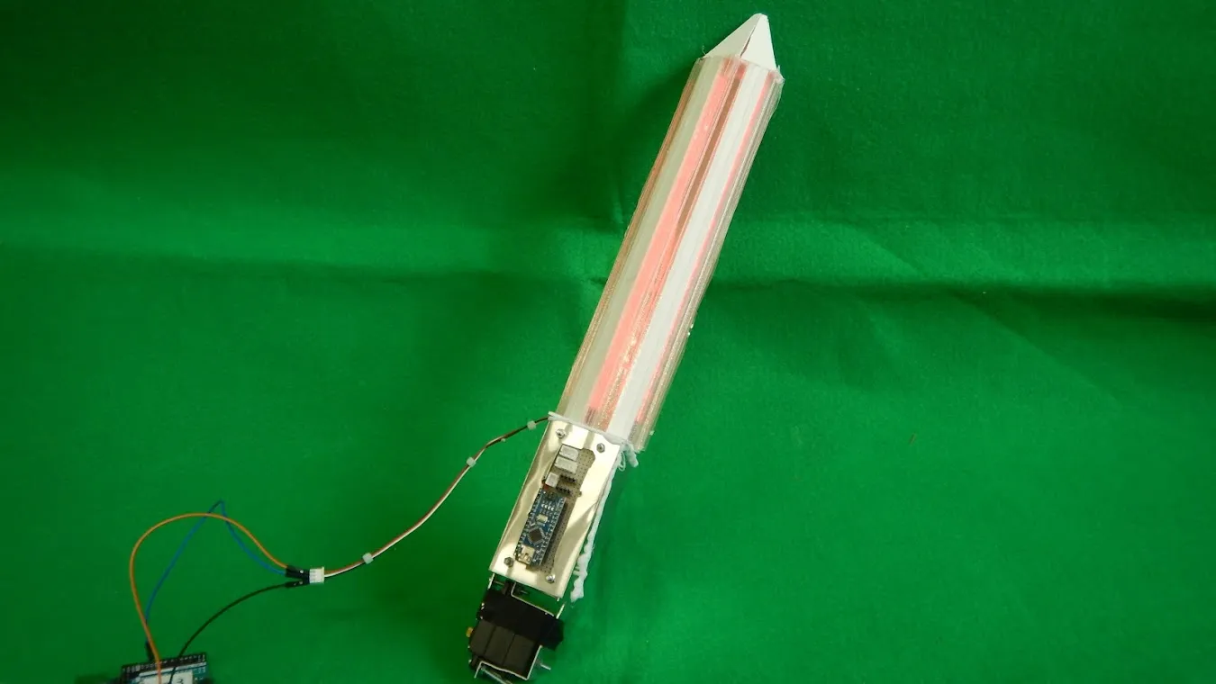 An illuminated sword-shaped device against a green background