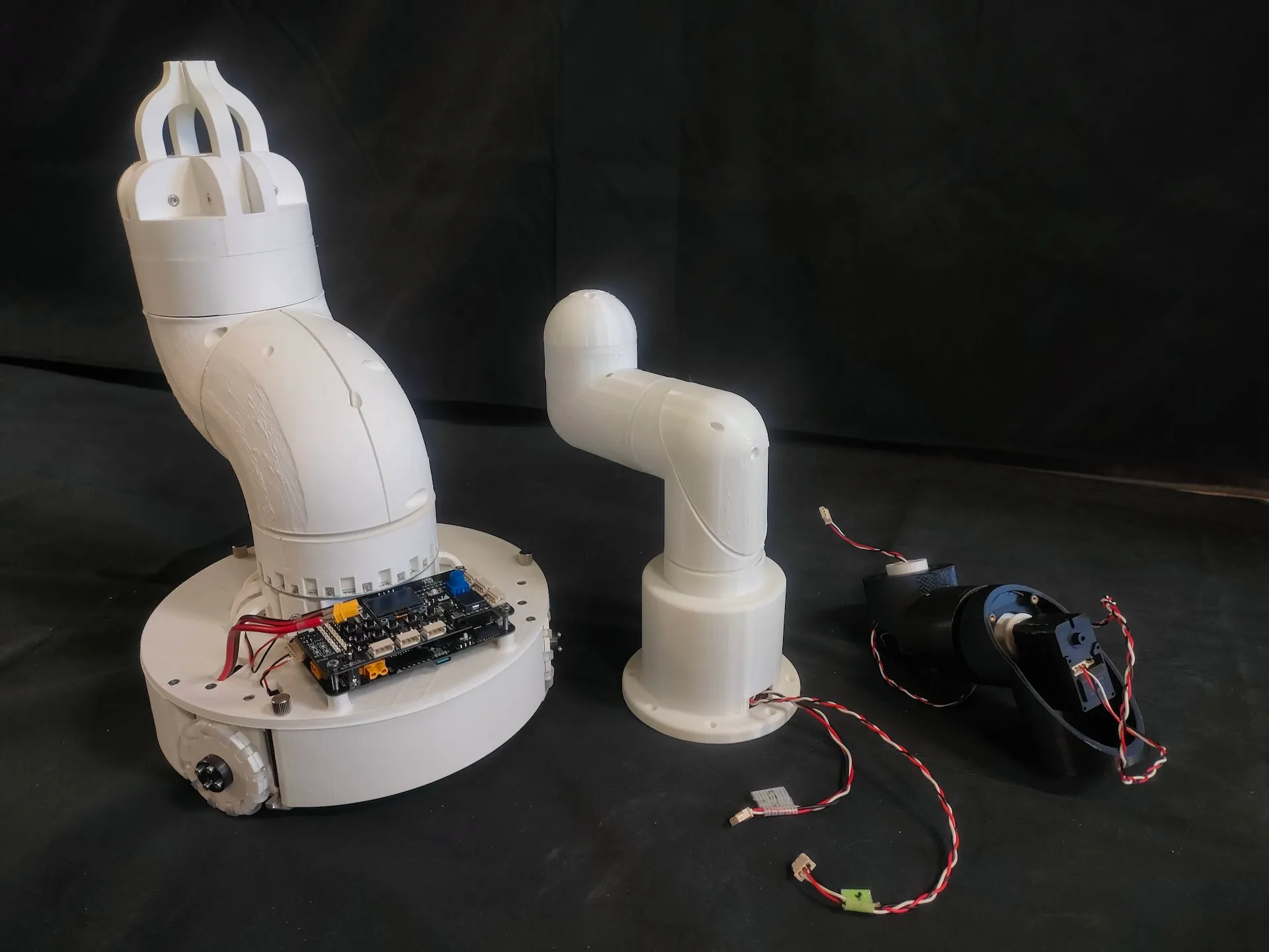 Three white robotic arm mechanisms arranged against a black backdrop