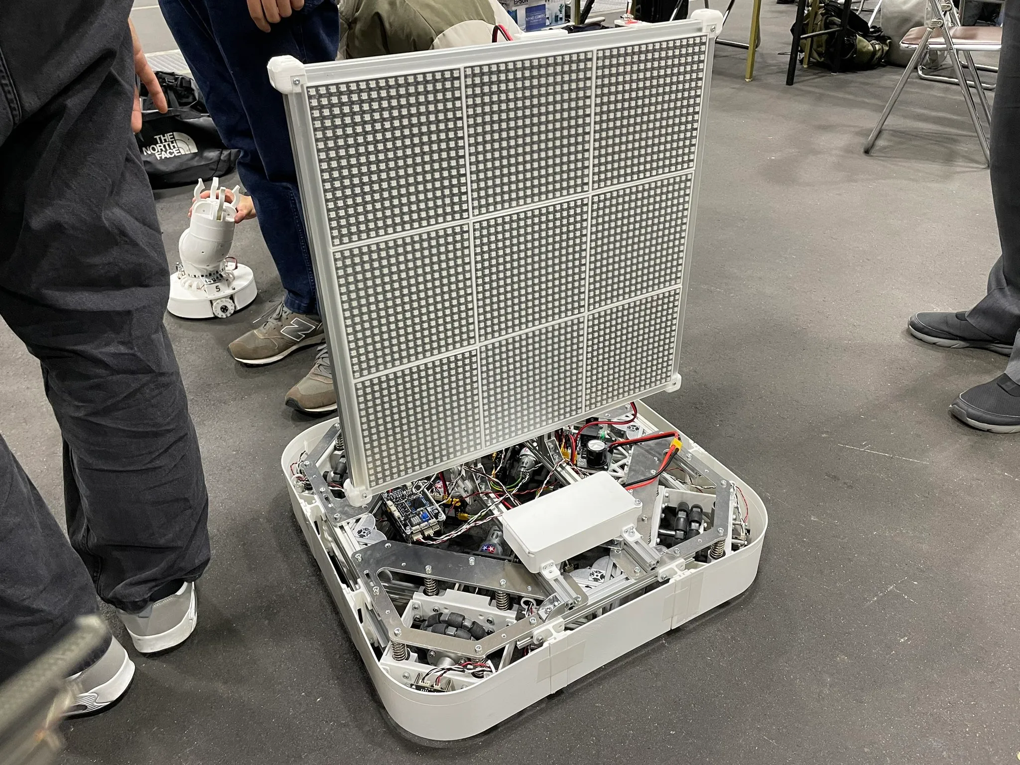 A mobile robot carrying a large square LED display at an exhibition