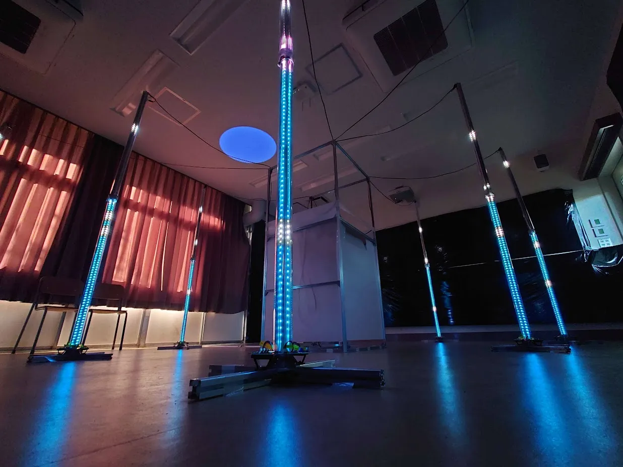 Several tall LED poles glowing blue across an indoor space