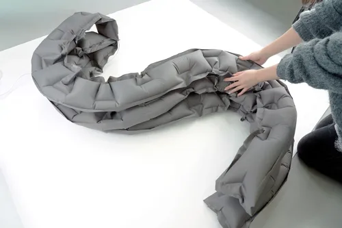 A gray inflatable tube arranged into a freeform curve on a worktable
