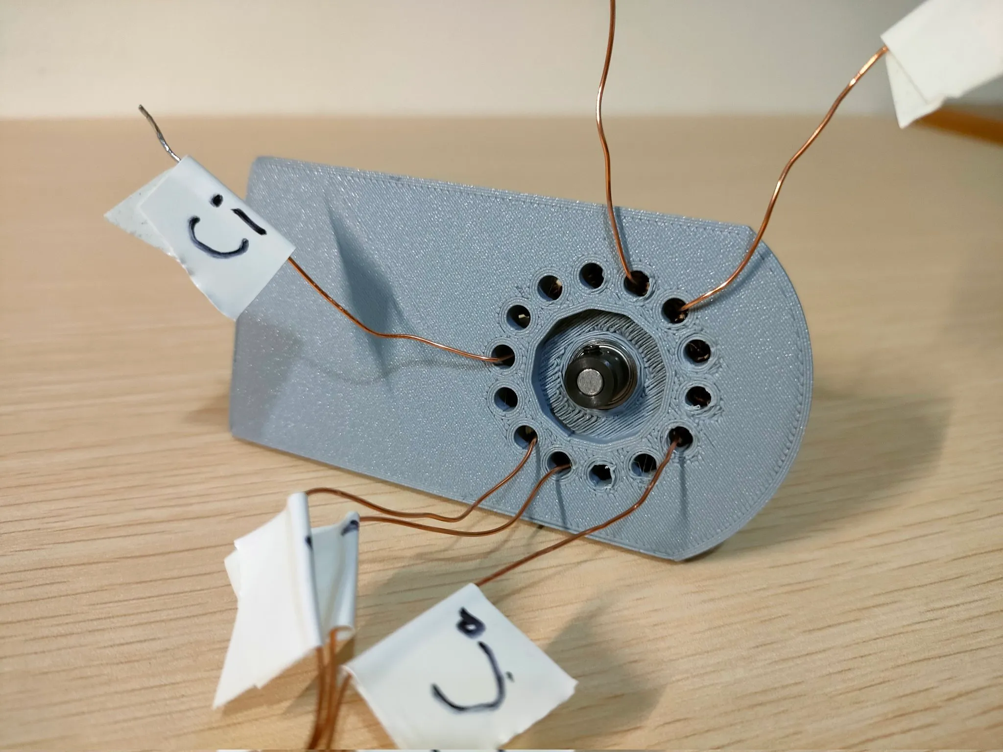 筐体から複数の銅線が伸びる3Dプリンタ製モーターの裏側